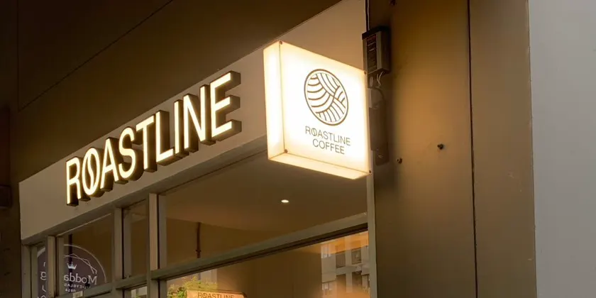 ป้ายไฟชื่อ ROASTLINE และป้ายโลโก้เหนือทางเข้าร้าน